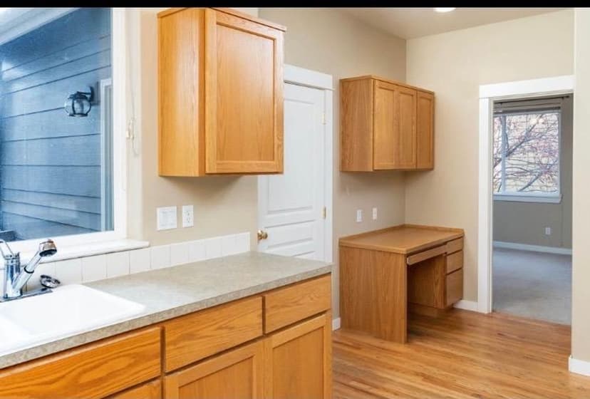 Bright kitchen with oak cabinets, a countertop, and a desk nook overlooking a window.
