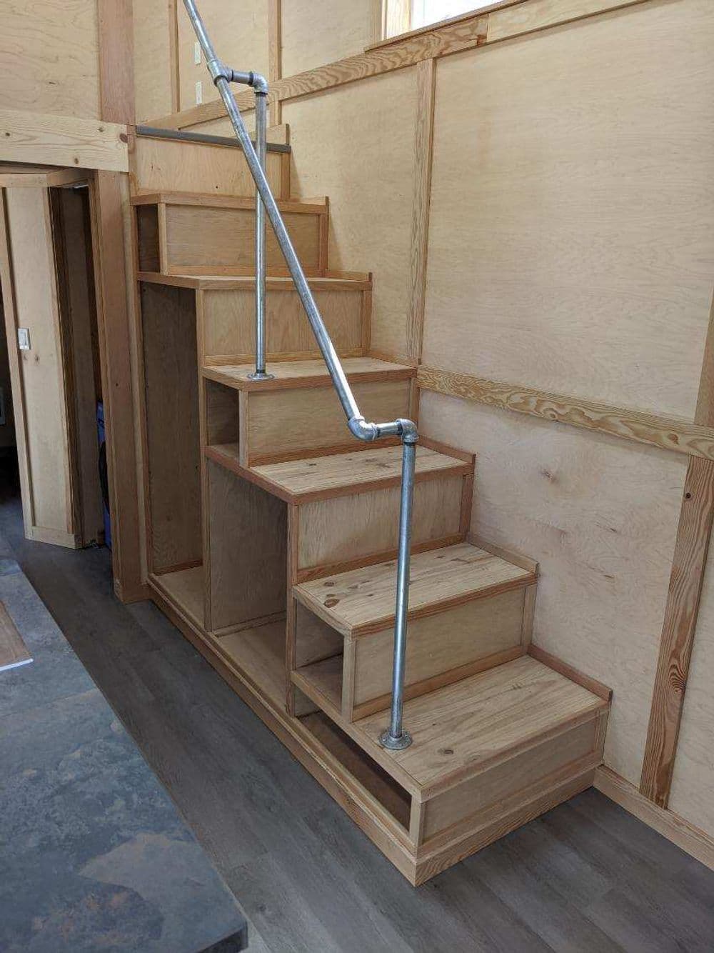 Modern wood staircase with built-in storage and metal handrail in minimalist interior design.