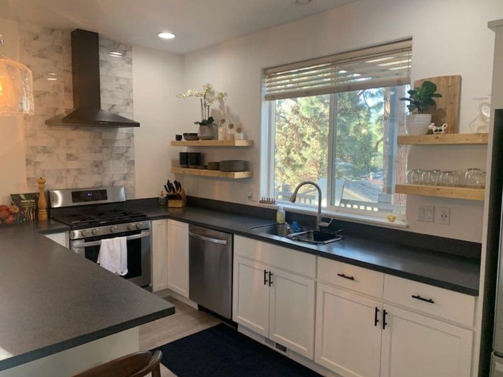 Modern kitchen with sleek appliances, open shelves, and abundant natural light from window.