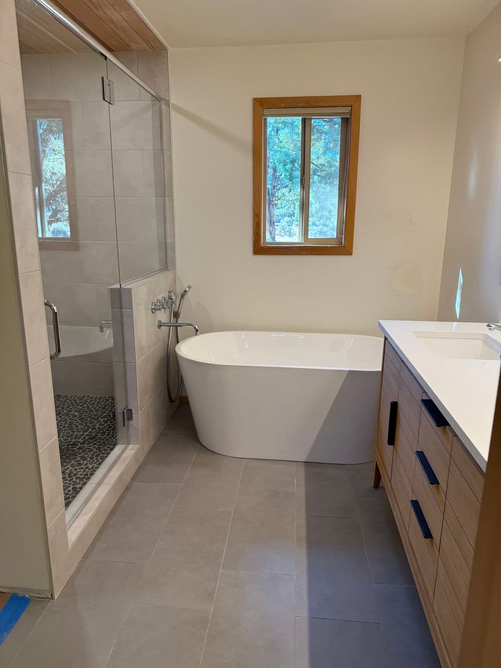 Modern bathroom featuring a freestanding tub, walk-in shower, and wooden vanity.