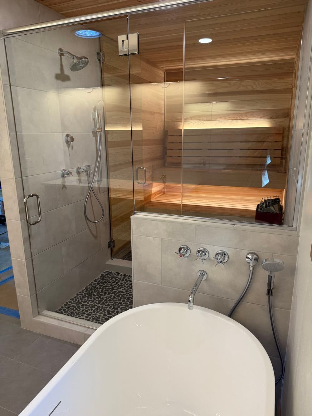 Modern bathroom featuring a glass shower, soaking tub, wood accents, and stylish tile work.