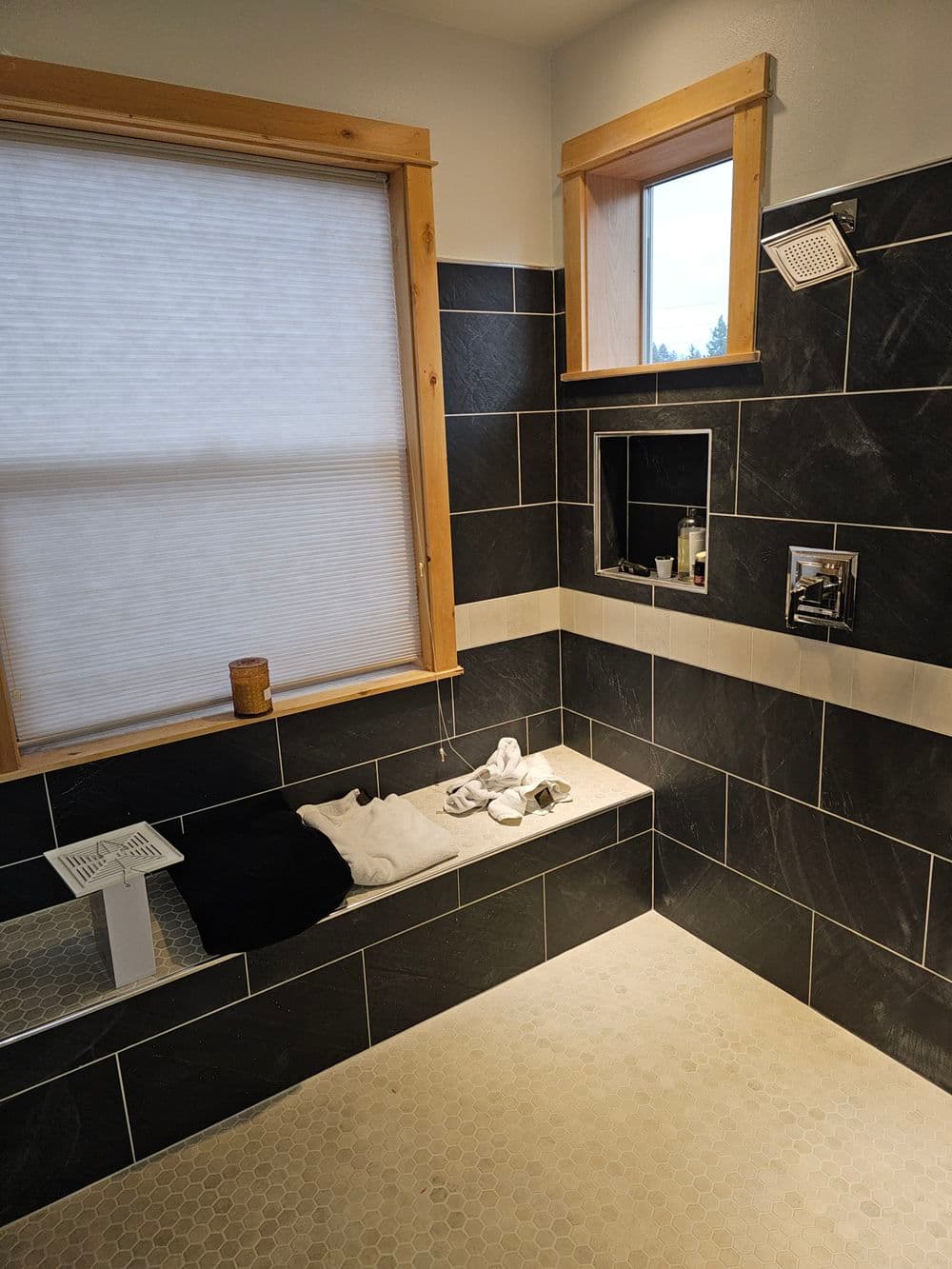 Modern bathroom with slate tile walls, natural light, and a built-in bench for relaxation.