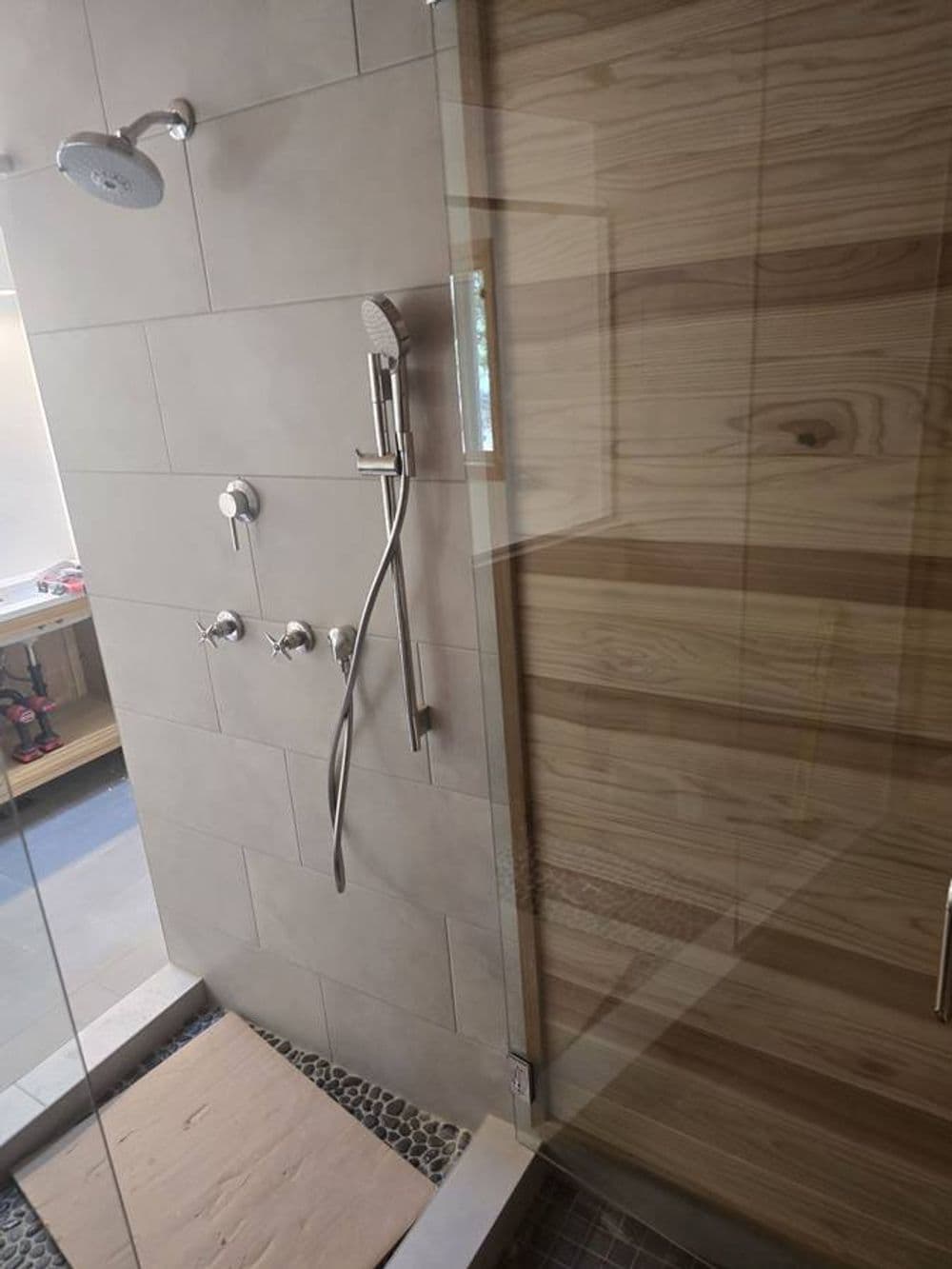 Modern shower design with glass enclosure, rainfall showerhead, and natural wood accents.