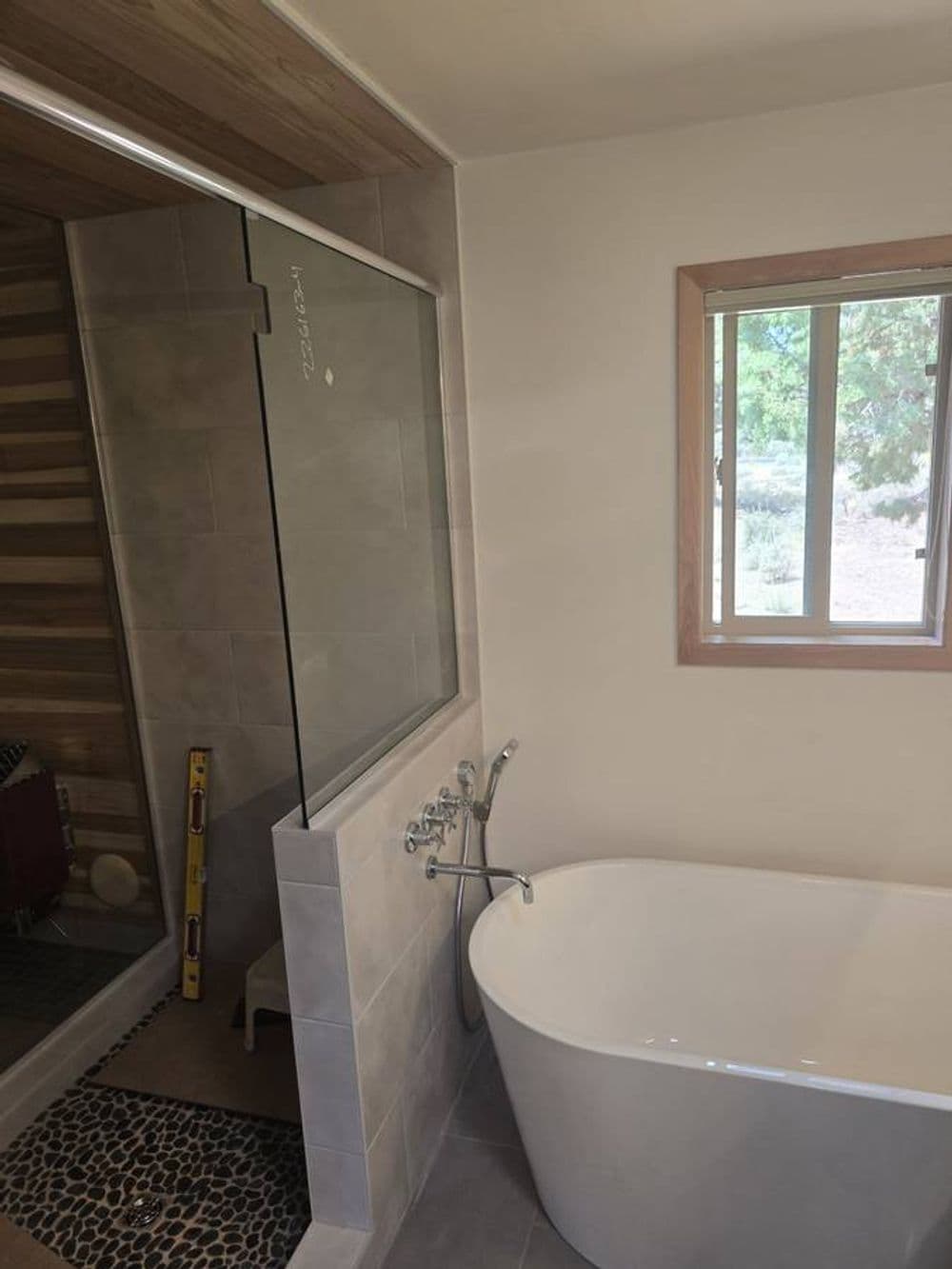 Modern bathroom featuring a freestanding tub, glass shower, and natural light from window.