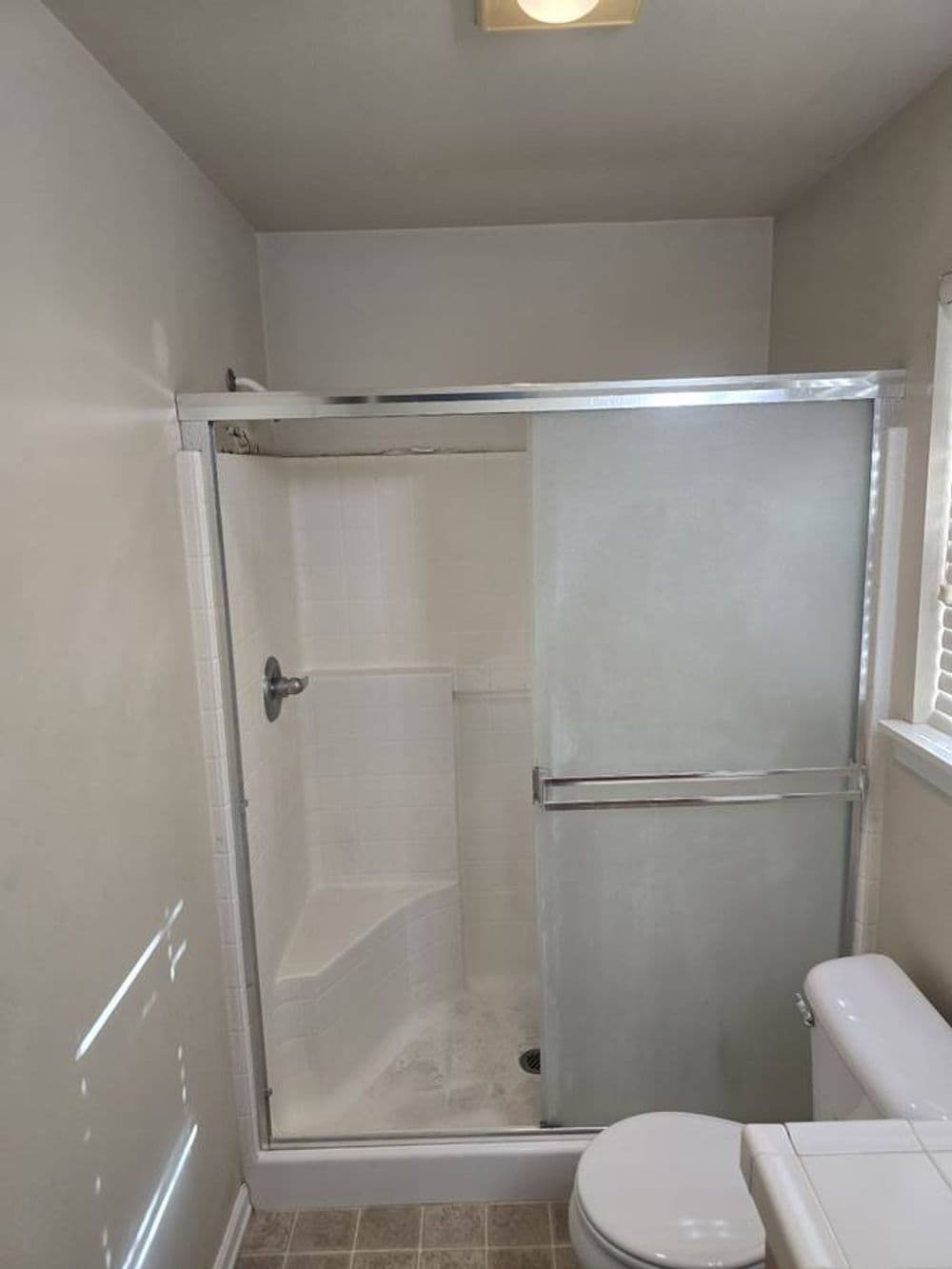 Modern bathroom featuring a glass shower enclosure and white tiles. Clean and well-lit space.