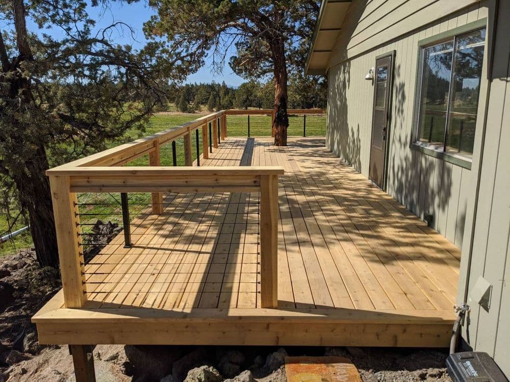 Spacious wooden deck with railing beside a house and scenic outdoor view.