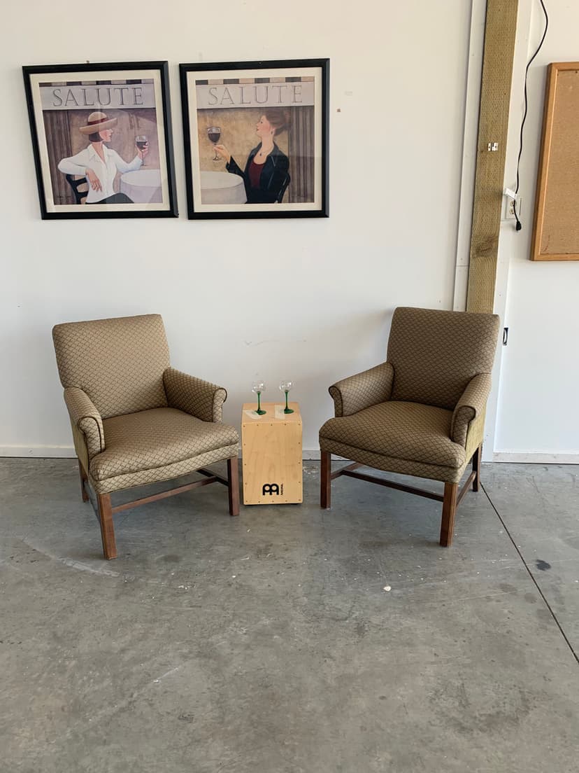 Two patterned chairs facing each other with a wooden side table and framed art on the wall.