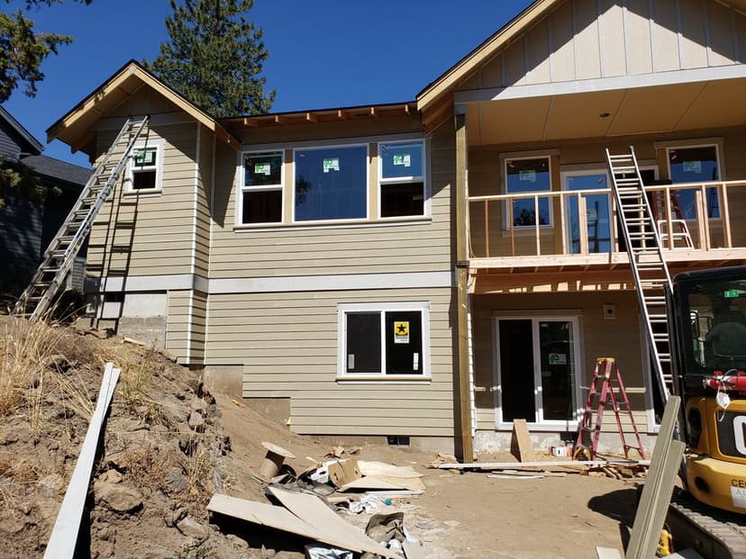 Newly constructed house with ladders, windows, and construction materials on site.