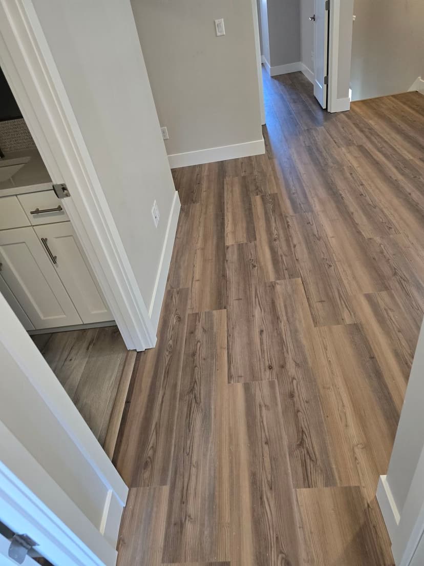 Modern interior hallway with brown laminate flooring and white trim, showcasing spacious design.
