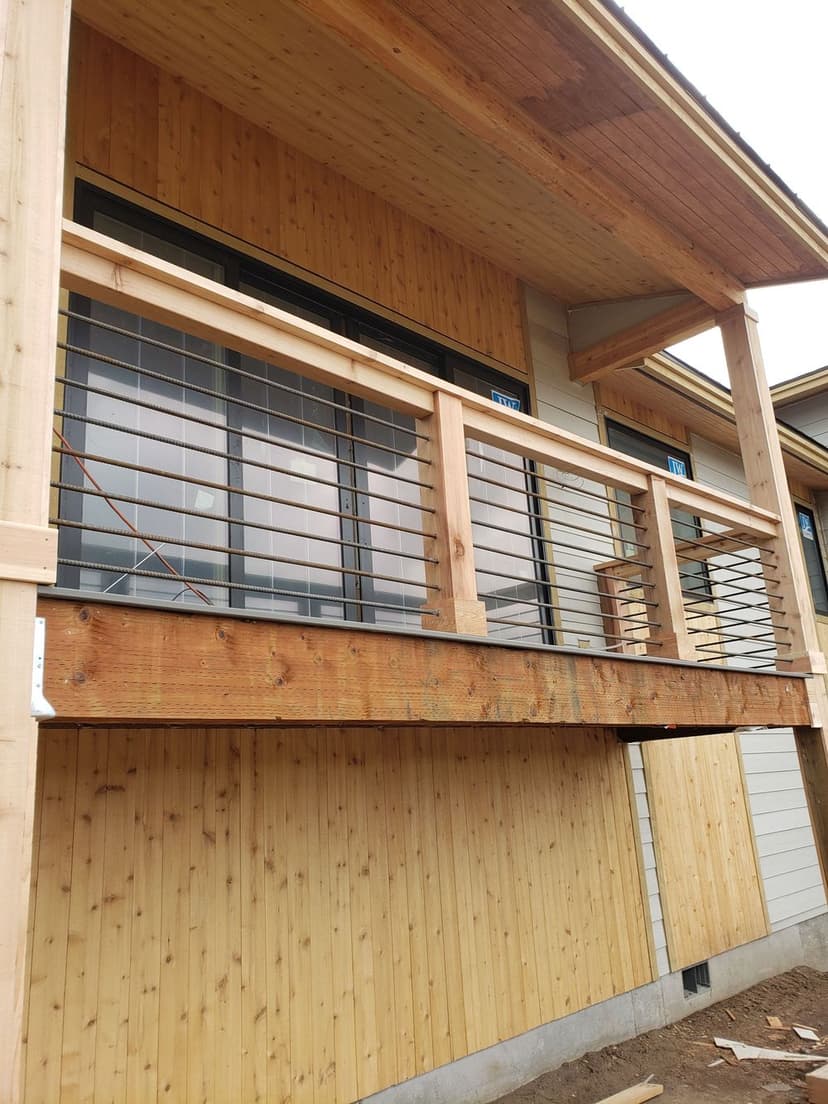 Wooden balcony with modern railing design, featuring natural wood finish against a plank wall.